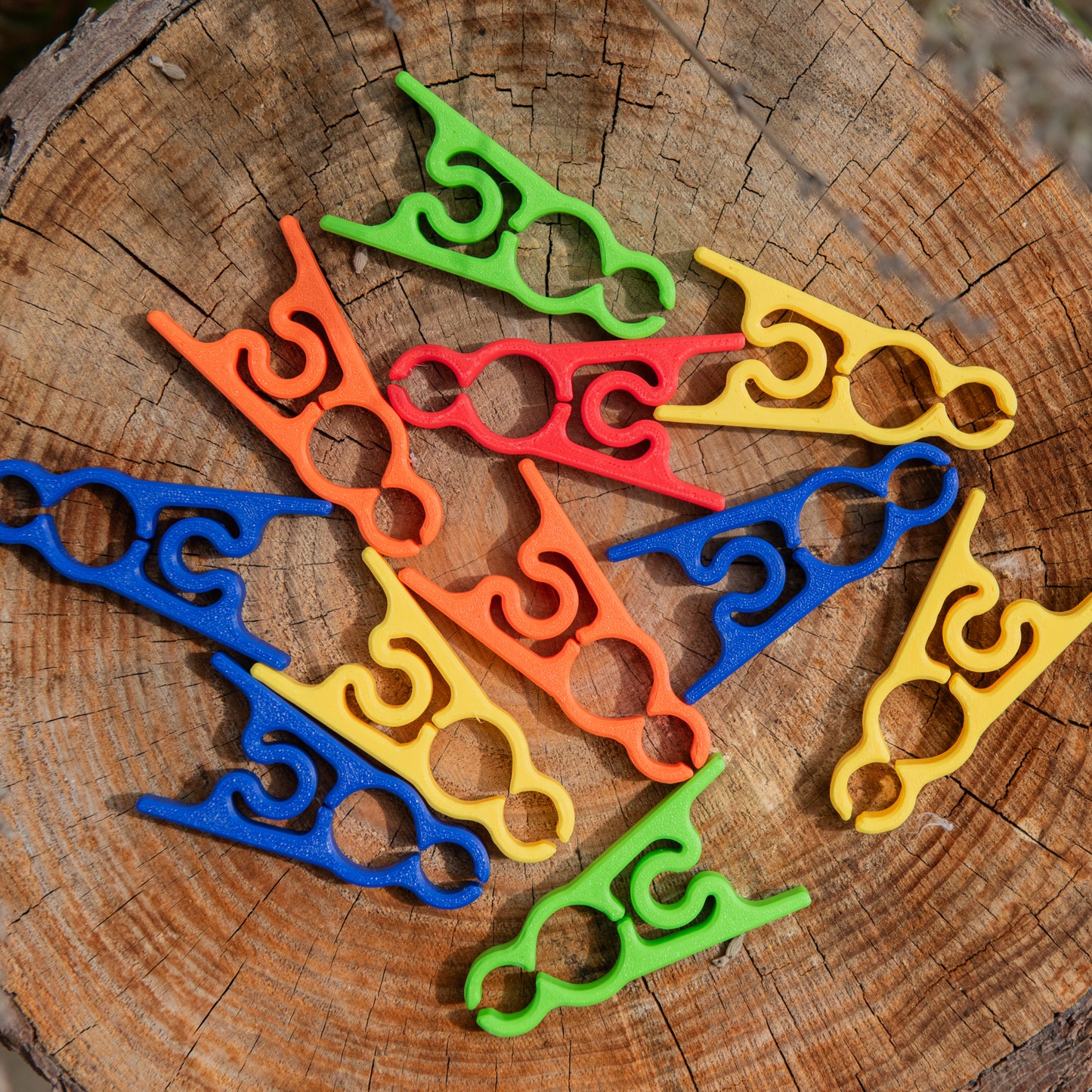 Flat lay of multicoloured garden clips on a wooden surface, showing red, blue, green, yellow, and orange clip options